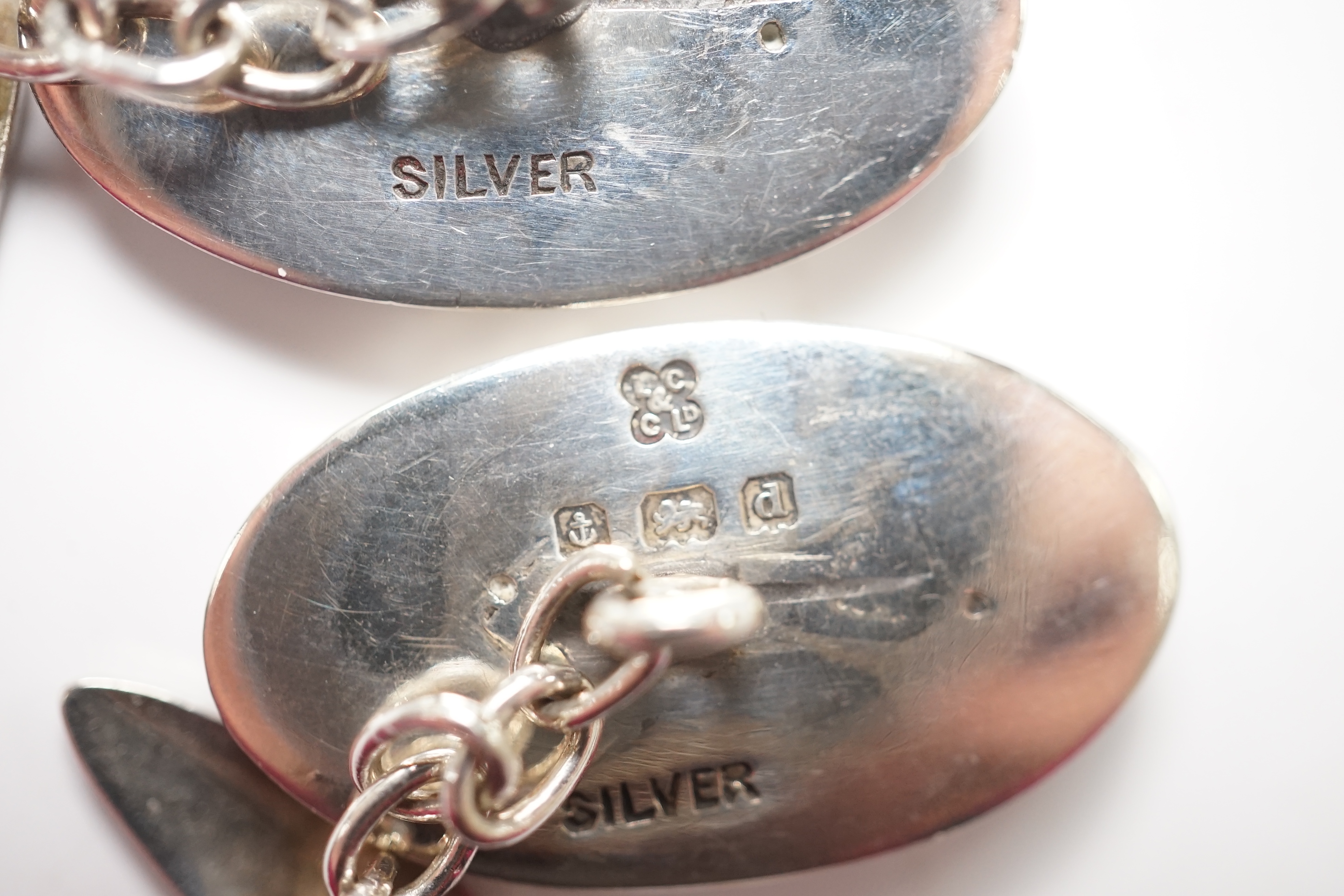 A pair of Edwardian Art Nouveau silver and enamel oval cufflinks, by Liberty & Co Ltd, 23mm, together with a garnet set bar brooch and a Hunt & Roskell box. Condition - poor to fair